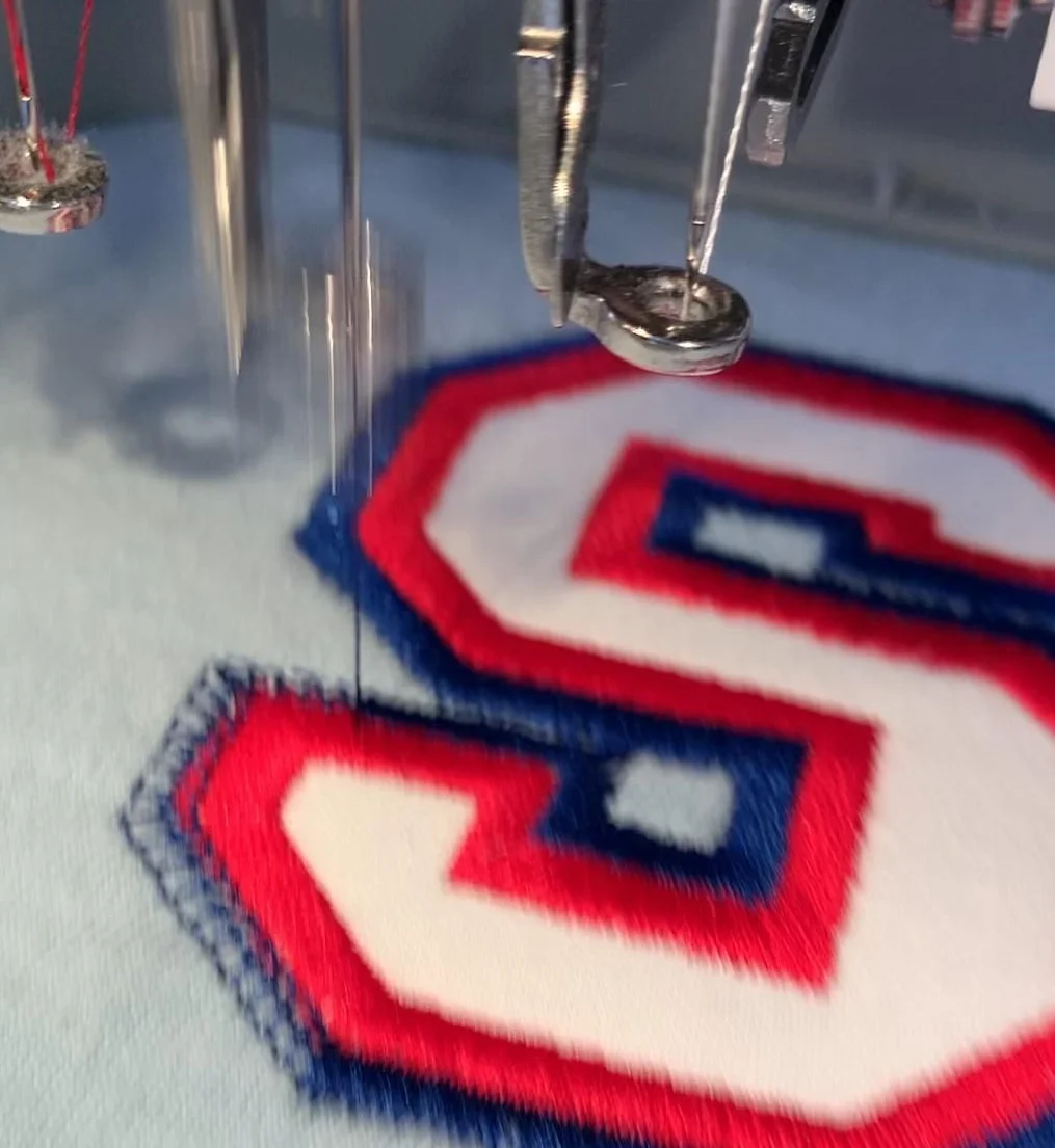 Embroidery machine stitching a custom letter patch at Vestiestilo